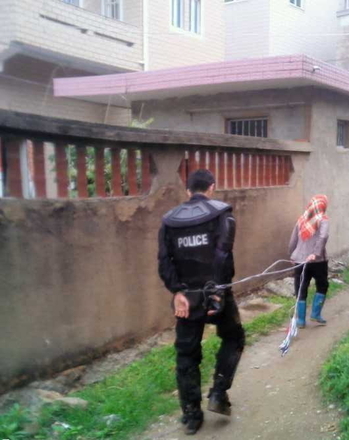 Uma mulher conduz um policial capturado após conflitos com as autoridades sobre a expropriação de terras no município de Dongwiao, província de Fujian, China, em 11 de maio de 2013 (Molihua.org)