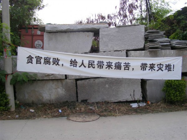 Aldeões enfrentam a polícia de choque durante disputas de terras com oficiais locais na vila de Nunhu, província de Fujian, China, em 11 de maio. Um cartaz diz, "Oficiais corruptos trazem sofrimento e desastre para o povo!" (Molihua.org)