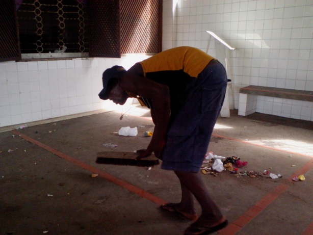 Morador varrendo o chão com uma vassoura sem cabo no abrigo na antiga Clínica Ana Nery, em Salvador, Bahia, em junho de 2013 (Miguel Campos / Epoch Times) 