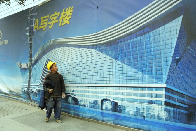 Um trabalhador passa por um outdoor do maior edifício independente do mundo em construção em Chengdu, capital da província de Sichuan, sudoeste da China. Chengdu continua movendo todos os recursos da província para a capital, enquanto todas as outras cidades em Sichuan definham (Sebastien Blanc/AFP/Getty Images)