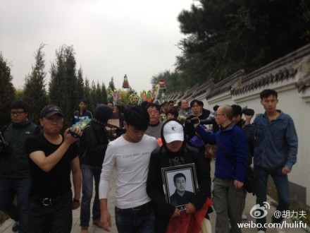 Acompanhado pela família e amigos, a filha de Xia Junfeng segurava a foto do pai a caminho do funeral (Weibo.com)