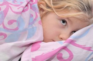 Imagem de uma criança deitada na cama via Shutterstock