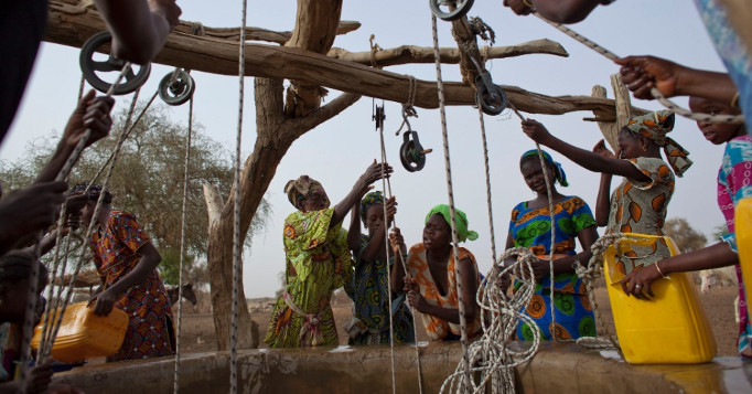 Mulheres se esforçando para retirar água de um poço de água na África.