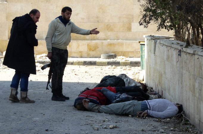 Rebeldes gesticulam ao lado dos corpos de homens mortos algemados e com os olhos vendados, depois de terem sido supostamente executados pelo grupo Al-Qaeda, no norte cidade de Aleppo, no dia 8 de janeiro de 2014 (MAHMUD AL-HALABI/AFP/Getty Images)