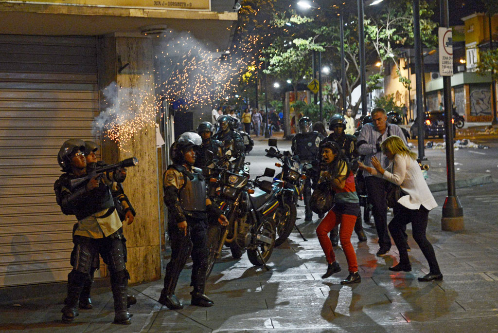 Um policial atira gás lacrimogêneo contra manifestantes antigoverno durante confrontos em Caracas, em 12 de junho de 2014. O governo venezuelano estaria se preparando para enfrentar crescente agitação interna (Leo Ramirez/AFP/Getty Images)