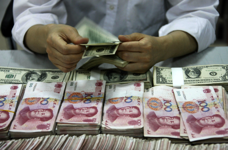  Notas de dólares americanos são contadas ao lado de pilhas de notas de banco chinês em um banco em Huaibei, província de Anhui, na China (STR / AFP / Getty Images)