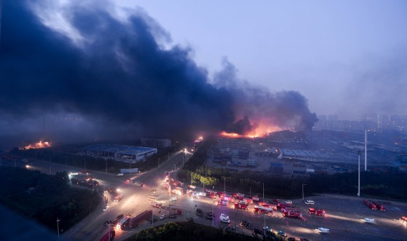 Fogo e fumaça sobre o local das massivas explosões em Tianjin, China, no dia 13 de agosto de 2015 (STR / AFP / Getty Images) 