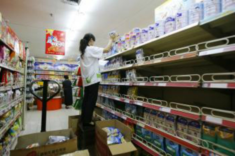 Uma funcionária remove o leite em pó contaminado por melamina da prateleira em um supermercado em Pequim, China (China Photos / Getty Images)