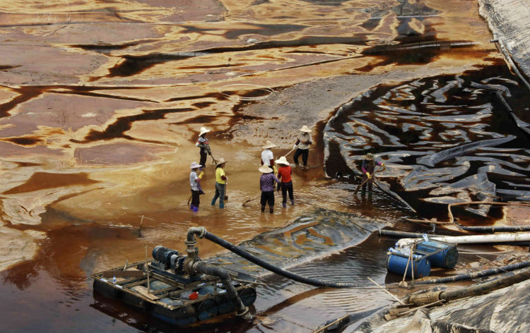Trabalhadores escorrem água poluída, perto da mina de cobre de Zijin, em Shanghang, em 2010 (STR / AFP / Getty Images)
