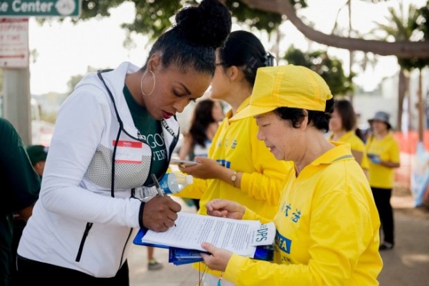 Judy Feng, de Nova Jersey, voluntários coletam assinaturas na praia de Santa Monica junto com praticantes de Falun Gong, vestindo camisetas amarelas, em 17 de outubro de 2015 (Cat Rooney/Epoch Times)