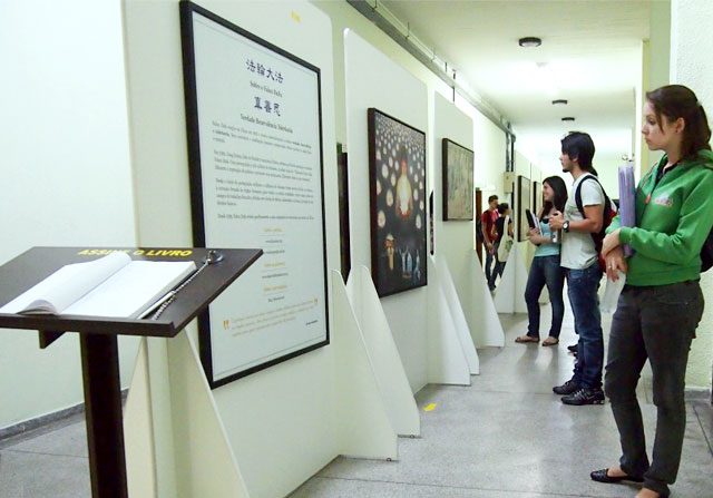 Visitantes observam os quadros na Exibição Internacional de Arte Verdade-Benevolência-Tolerância na USF, nesta segunda-feira, 1º de outubro (Ticiane Rossi / The Epoch Times)