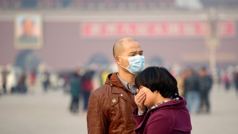 Um casal na Praça da Paz Celestial em Pequim. Segundo estimativas recentes, a poluição causada pelo descaso do Partido Comunista Chinês deverá gerar um milhão de pacientes com câncer de pulmão até 2025 (Wang Zhao/AFP/Getty Images)