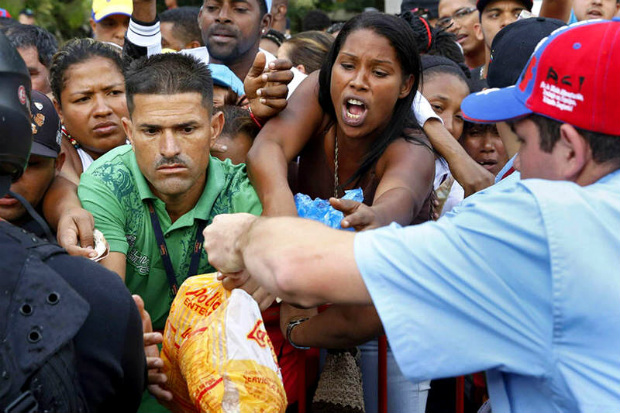 Pessoas fazem fila para comprar frango atrás de uma cerca em um mercado de rua em Caracas, em 24 de janeiro de 2015 (JUAN BARRETO/AFP/Getty Images)