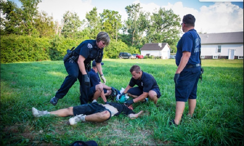 Polícia local e paramédicos administram Narcan, um bloqueador de opioides, para ressuscitar um homem em estado de overdose no bairro de Drexel em Dayton, Ohio, em 3 de agosto de 2017 (Benjamin Chasteen/Epoch Times)