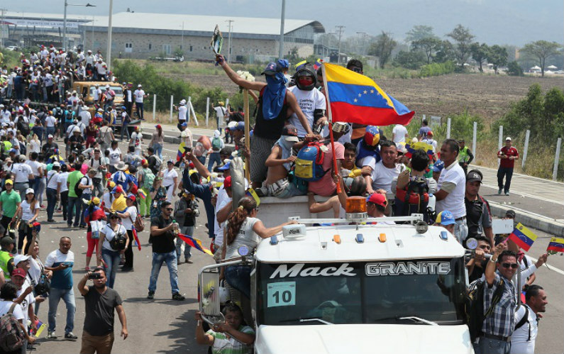 Cidadãos venezuelanos se deslocam em caminhões, neste sábado, em Cúcuta (Colômbia). Centenas de venezuelanos se reuniram no sábado no lado colombiano da ponte internacional Simón Bolívar, que liga Cúcuta a San Antonio, no estado venezuelano de Táchira, para formar um corredor que facilite a passagem da ajuda humanitária para seu país (Mauricio Dueñas Castañeda/EFE)