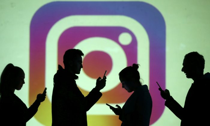Silhuetas de usuários de celular são vistas ao lado de uma projeção de tela do logotipo do Instagram nesta foto ilustração tirada em 28 de março de 2018 (Dado Ruvic / Reuters)