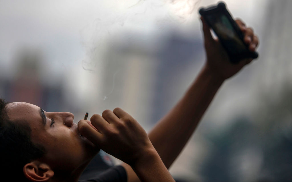 Homem fuma um baseado durante protestos de rua pedindo a legalização da maconha na Avenida Paulista em São Paulo, Brasil, em 1º de junho de 2019 (MIGUEL SCHINCARIOL / AFP / Getty Images)