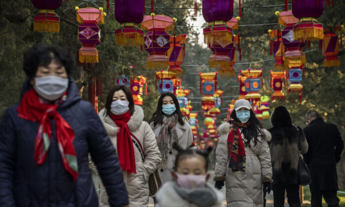 Transeuntes usam máscaras protetoras enquanto andam sob as decorações do Ano Novo Chinês em um parque em Pequim, China, em 25 de janeiro de 2020 (Kevin Frayer / Getty Images)