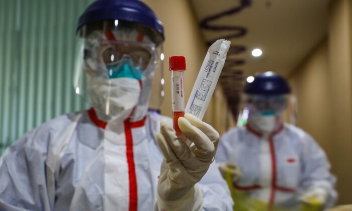 Membro da equipe médica mostra um tubo de ensaio após colher amostras de uma pessoa a ser testada para o novo coronavírus em uma área de quarentena em Wuhan, China, em 4 de fevereiro de 2020 (STR / AFP via Getty Images)