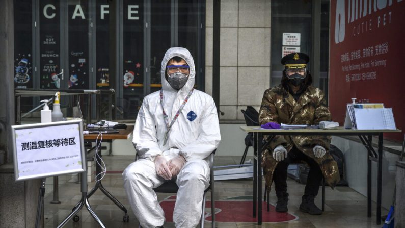 Um guarda chinês com uma máscara e um traje protetor espera para aferir as temperaturas e registrar as pessoas que entraram em um edifício em uma zona comercial de Pequim, China, 21 de fevereiro de 2020 (Kevin Frayer / Getty Images)