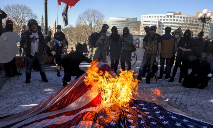 Membros do Partido Comunista dos EUA e de outros grupos antifascistas queimam uma bandeira americana nos degraus do Capitólio do Estado do Colorado em Denver, Col., em 20 de janeiro de 2021 (Michael Ciaglo / Getty Images)
