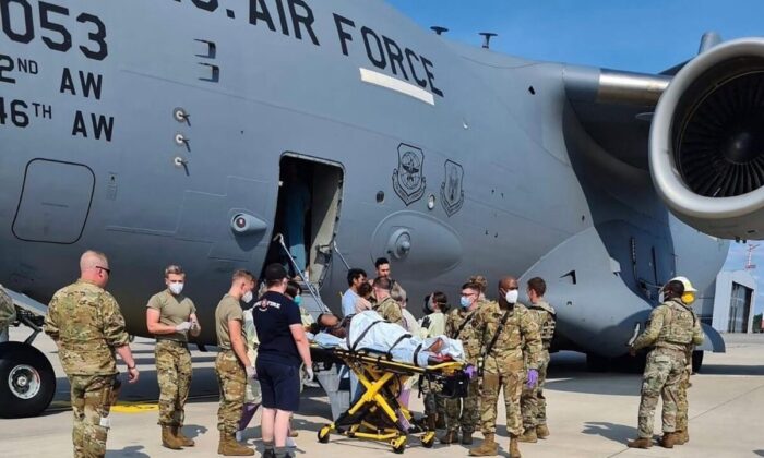 Equipe de apoio médico ajuda uma mãe afegã e família em um C-17 da Força Aérea dos EUA, momentos depois que ela deu à luz uma criança a bordo da aeronave ao pousar na Base Aérea de Ramstein, Alemanha, em 21 de agosto de 2021. (Comando de Mobilidade Aérea dos EUA via Reuters )
