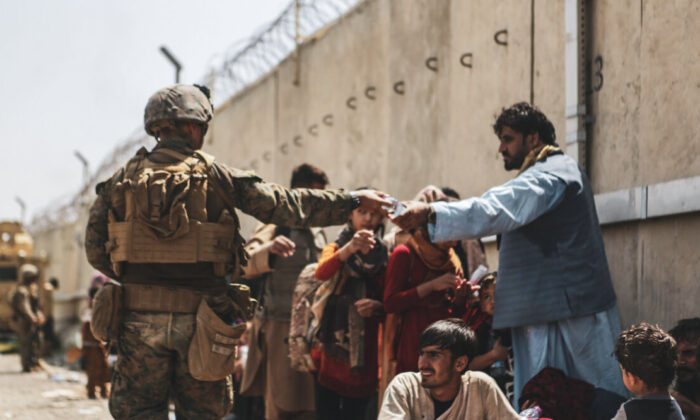 Um fuzileiro naval da 24ª Unidade Expedicionária de Fuzileiros Navais (MEU) entrega água para evacuados do Afeganistão no Aeroporto Internacional Hamid Karzai em Cabul em 21 de agosto de 2021. (Isaiah Campbell / Corpo de Fuzileiros Navais dos Estados Unidos via Getty Images)
 