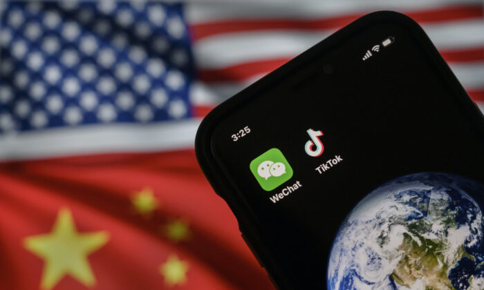 Um celular pode ser visto exibindo os logotipos dos aplicativos chineses WeChat e TikTok em frente a um monitor que mostra as bandeiras dos Estados Unidos e da China em uma página da internet, em Pequim, no dia 22 de setembro de 2020 (Kevin Frayer / Getty Images)