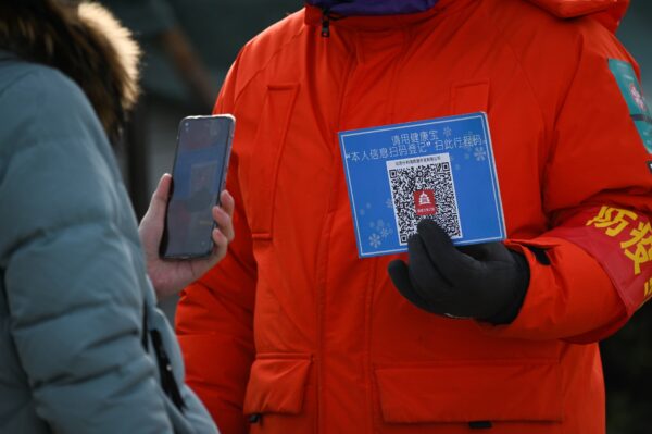 Uma mulher usa seu celular para escanear um código QR para registro de saúde antes de entrar em uma pista de gelo ao ar livre em Pequim, em 12 de janeiro de 2021 (Wang Zhao / AFP via Getty Images)