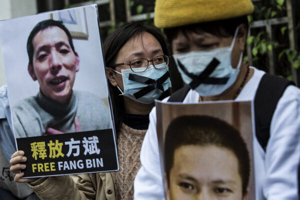 Uma ativista pró-democracia (C) da HK Alliance segura um cartaz do jornalista cidadão desaparecido. Fang Bin, enquanto ela protesta fora do escritório de ligação chinês em Hong Kong, em 19 de fevereiro de 2020 (Isaac Lawrence / AFP via Getty Images)