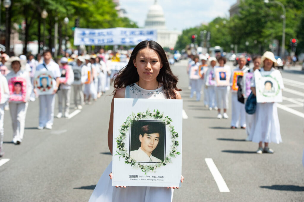 Uma mulher segura uma foto de um homem morto pela perseguição do regime chinês ao Falun Gong, durante um desfile em Washington, no dia 17 de julho de 2014 (Larry Dye/Epoch Times)