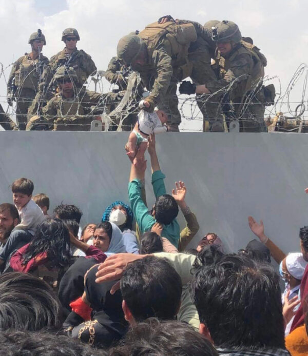 Esta imagem fornecida à AFP, no dia 20 de agosto de 2021, pelo ativista de direitos humanos Omar Haidari, mostra um fuzileiro naval dos EUA segurando um bebê sobre uma cerca de arame farpado durante uma evacuação no Aeroporto Internacional Hamid Karzai, de Cabul, no dia 19 de agosto de 2021 (Cortesia de Omar Haidiri / AFP)