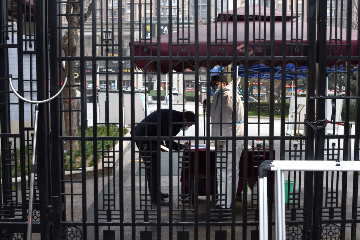 Guarda verifica as informações de um residente na entrada de uma área residencial que está sob restrições após um recente surto de coronavírus, em Xian, na província de Shaanxi, no norte da China, no dia 23 de dezembro de 2021 (STR / AFP via Getty Images)