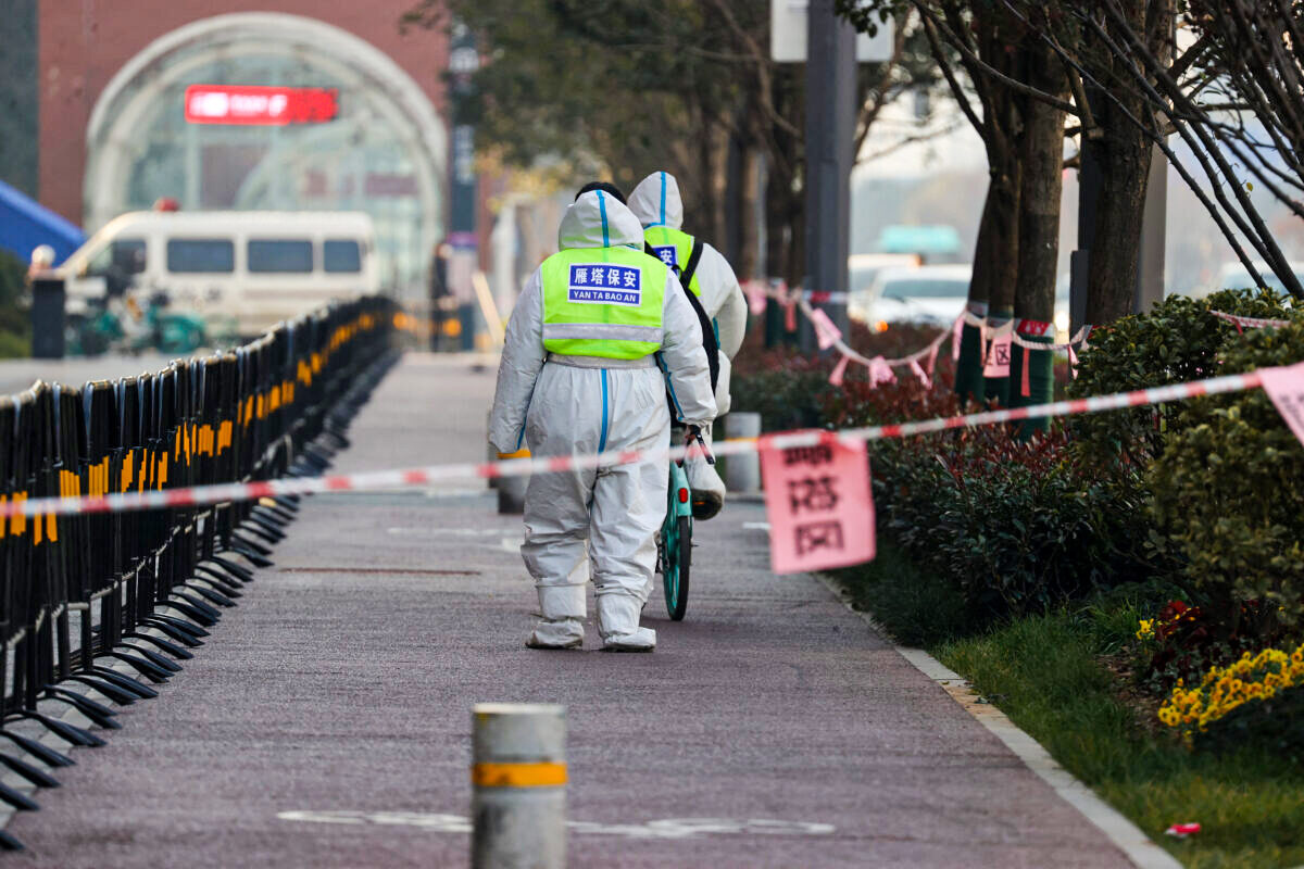 Guardas de segurança caminhando em uma área que está sob restrições após um surto recente da COVID-19 na cidade de Xi'an, na província de Shaanxi, na China, no dia 22 de dezembro de 2021 (STR / AFP via Getty Images)