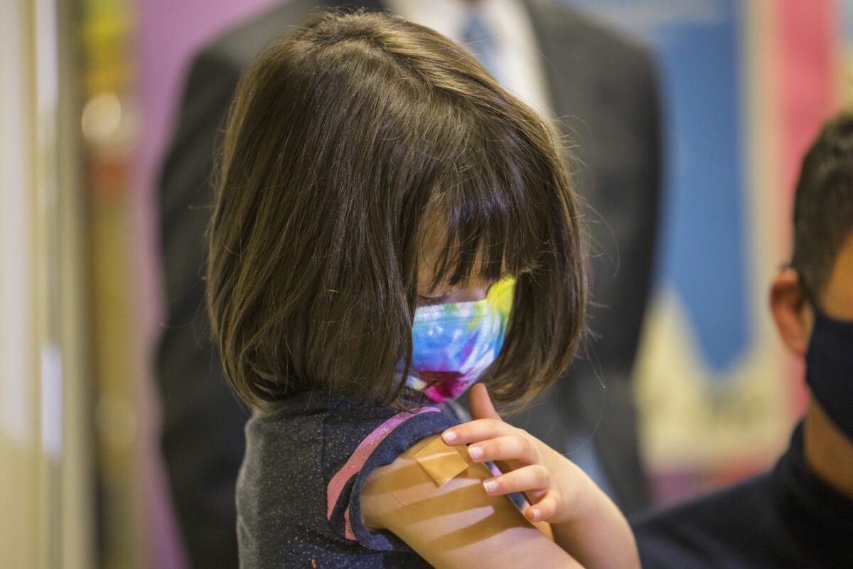 A 5-year-old girl looks at her arm after receiving a Pfizer vaccine against COVID-19 in New York City, November 8, 2021. (Michael M. Santiago/Getty Images)
