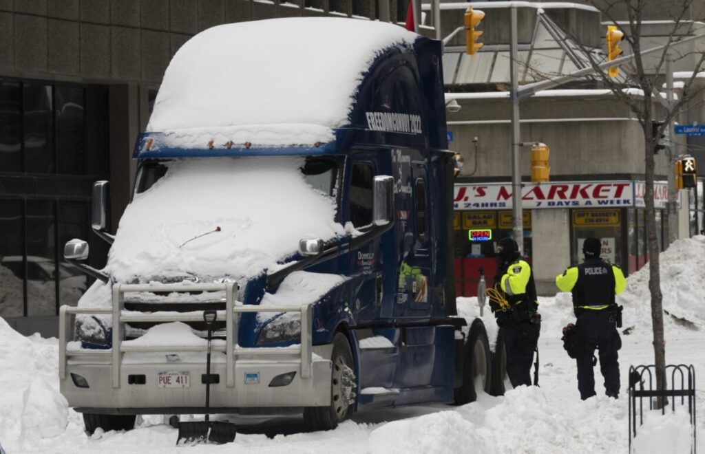 A polícia inspeciona um dos poucos caminhões de protesto restantes antes de rebocá-lo para fora do centro da cidade, em Ottawa, no dia 20 de fevereiro de 2022 (The Canadian Press/Adrian Wyld)
