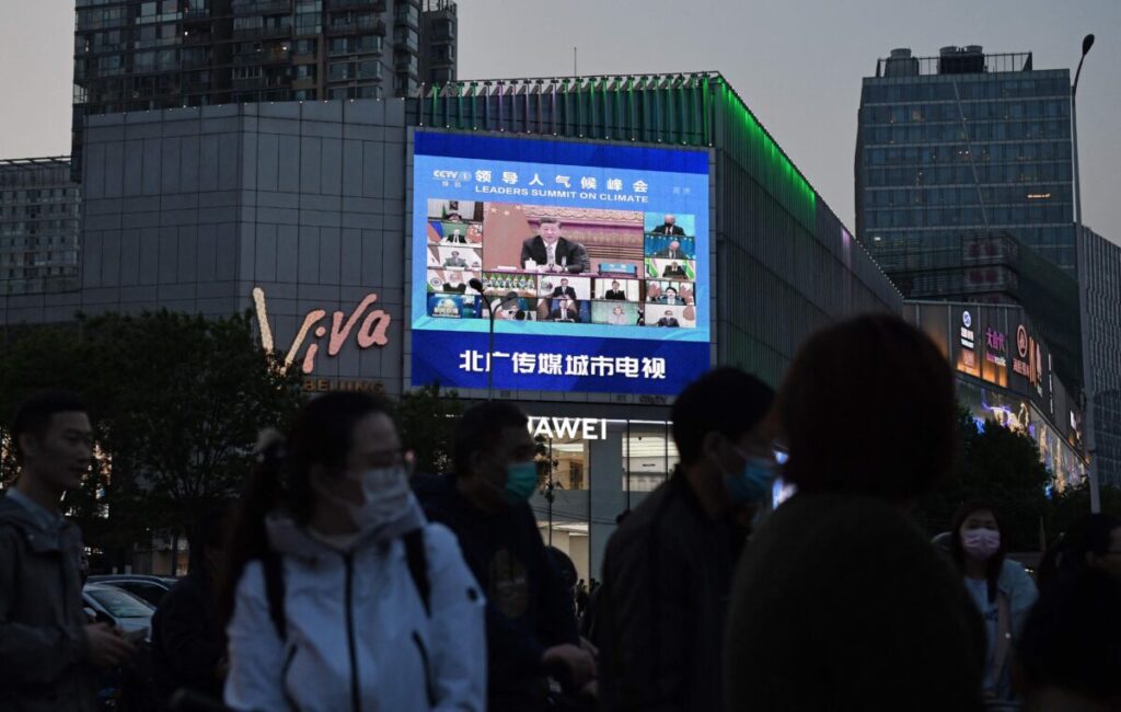 Uma reportagem de um programa de notícias sobre a aparição do líder do PCCh, Xi Jinping, em uma cúpula do clima liderada pelos EUA é vista em uma tela gigante em Pequim, no dia 23 de abril de 2021 (Greg Baker/AFP via Getty Images)