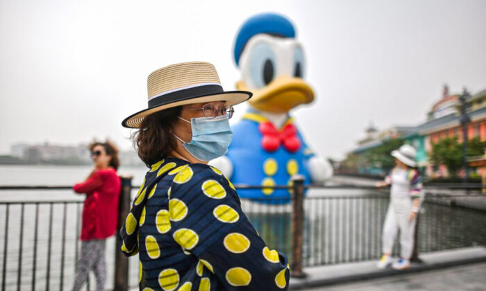 Uma mulher usando uma máscara facial visita a Disney Town, em Xangai, no dia 11 de maio de 2020. A Disneyland Shanghai reabriu no dia 11 de maio ao público após ser fechada desde janeiro de 2020 devido ao surto de coronavírus (HECTOR RETAMAL/AFP via Getty Images)
