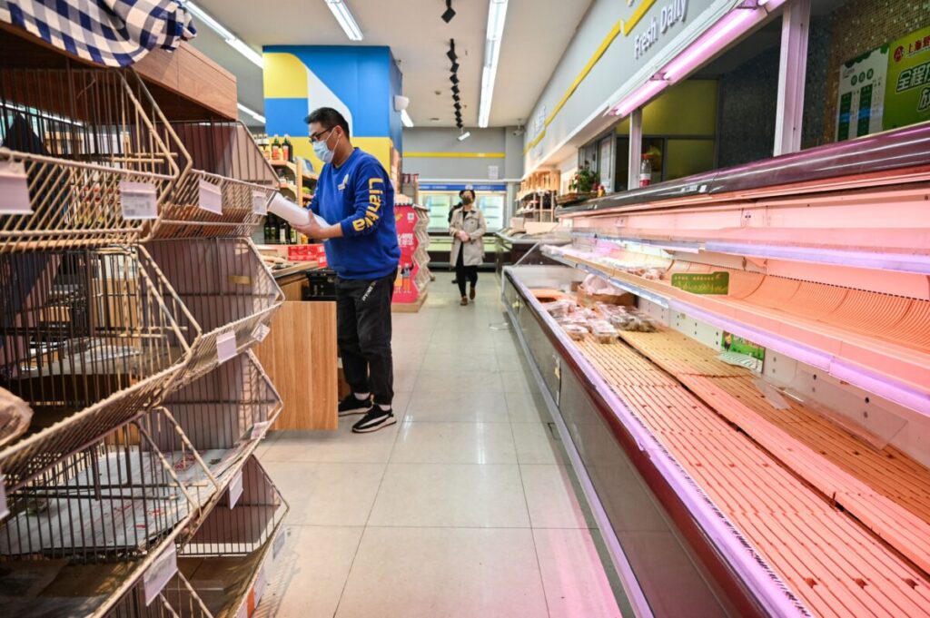 Os compradores vasculham prateleiras vazias em um supermercado antes de um bloqueio como medida contra a COVID-19 em Xangai, em 29 de março de 2022 (Hector Retamal/AFP via Getty Images)