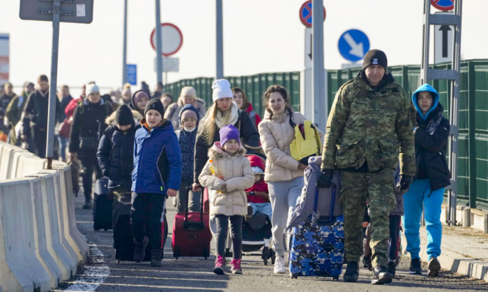 Um guarda de fronteira polonesa ajuda refugiados da Ucrânia quando chegam à Polônia na fronteira de Korczowa, na Polônia, no dia 26 de fevereiro de 2022 (Czarek Sokolowski/AP Photo)
