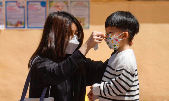 Uma mulher ajusta a máscara de uma criança em Hong Kong no dia 9 de março de 2022 (Vincent Yu / AP Photo)