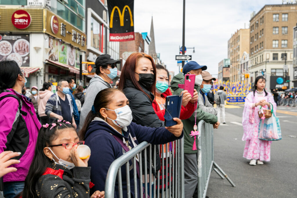 Espectadores se juntam aos praticantes do Falun Gong em um desfile para comemorar o 23º aniversário do apelo pacífico de 10.000 praticantes do Falun Gong em Pequim em 25 de abril, em Flushing, NY, no dia 23 de abril de 2022 (Chung I Ho/Epoch Times)
