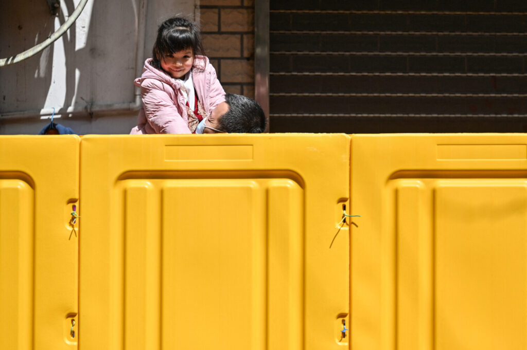 Um pai segura sua filha atrás de barreiras que separam um bairro em confinamento como medida contra a COVID-19 no distrito de Jing'an, em Xangai, em 29 de março de 2022 (Hector Retamal/AFP via Getty Images)