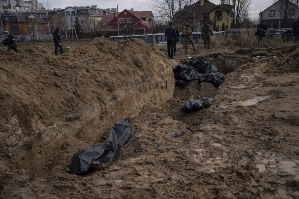 Jornalistas trabalham ao lado de uma vala comum em Bucha, nos arredores de Kiev, na Ucrânia, em 4 de abril de 2022 (AP Photo/Rodrigo Abd)