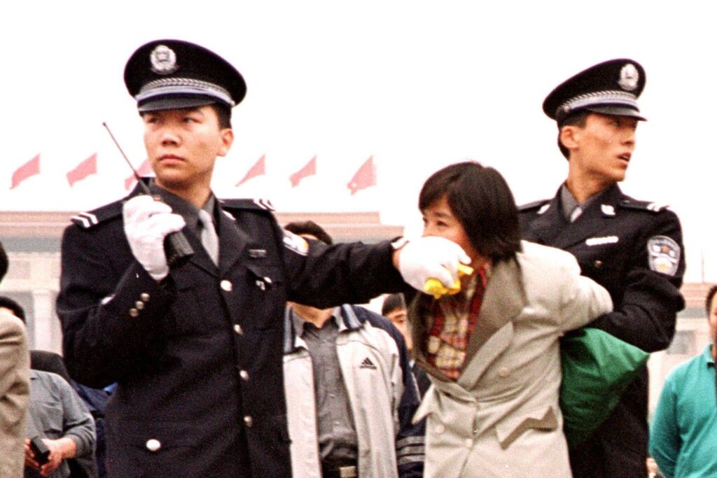 Dois policiais chineses prendem um praticante do Falun Gong na Praça Tiananmen, em Pequim, em 10 de janeiro de 2000 (Foto Chien-Min Chung/AP)