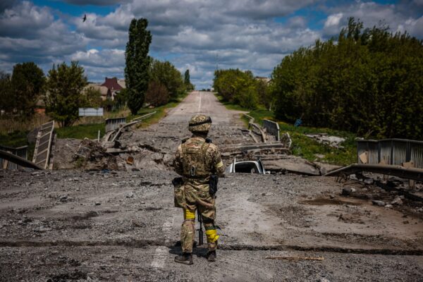 Um soldado das forças especiais ucranianas Kraken observa a área em uma ponte destruída na estrada perto da vila de Rus'ka Lozova, ao norte de Kharkiv, em 16 de maio de 2022 (Dimitar Dilkoff/AFP via Getty Images)