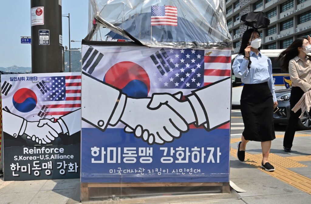 Pedestres passam por faixas pedindo o fortalecimento da aliança Coreia do Sul-EUA perto da embaixada dos EUA em Seul em 20 de maio de 2022, antes da visita do presidente dos EUA, Joe Biden, à Coreia do Sul (Jung Yeon-je/AFP via Getty Images)