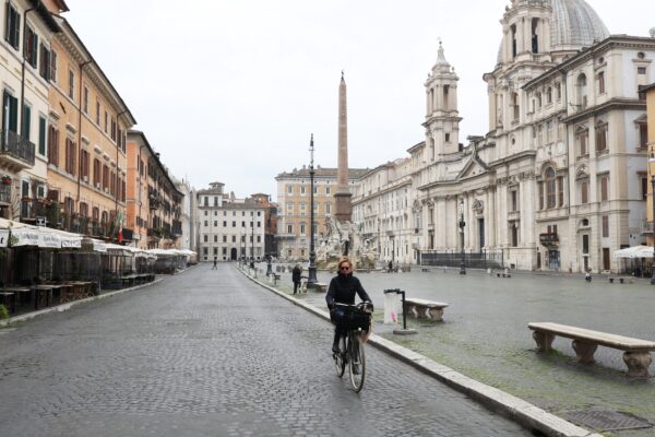 Uma mulher é vista andando de bicicleta na Praça Navona completamente vazia em Roma, em 13 de março de 2020. As ruas da cidade estavam estranhamente silenciosas no segundo dia de fechamento nacional de escolas, lojas e outros locais públicos (Marco Di Lauro/Getty Images)
