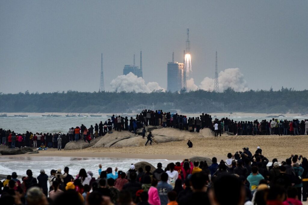 Pessoas assistem a um foguete Longa Marcha-8, a mais recente frota de veículos de lançamento da Longa Marcha da China, enquanto decola do Centro de Lançamento Espacial Wenchang, na província de Hainan, no sul da China, em 22 de dezembro de 2020 (STR/AFP via Getty Images)