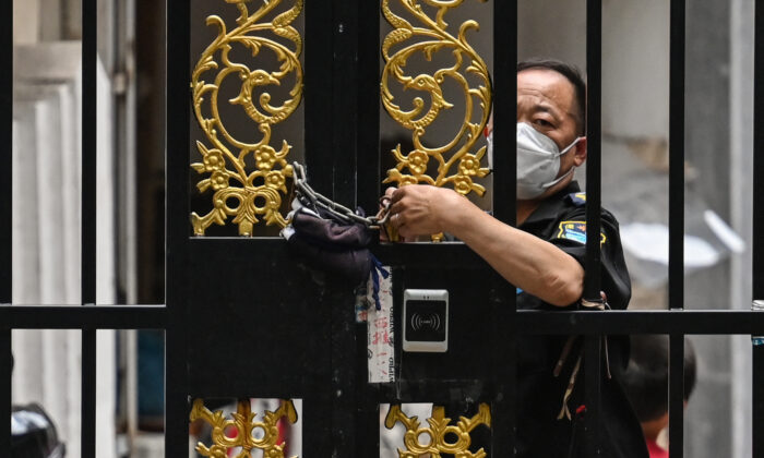 Um segurança tranca uma porta com uma corrente em um bairro sob um lockdown da COVID-19 no distrito de Jing'an, em Xangai, em 2 de junho de 2022 (Hector Retamal/AFP via Getty Images)